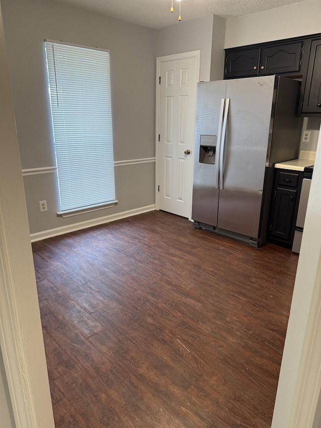 kitchen featuring light countertops, dark wood-style flooring, baseboards, and stainless steel fridge