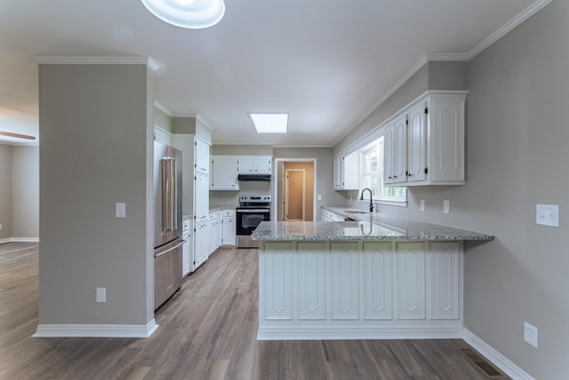 kitchen with a peninsula, a sink, appliances with stainless steel finishes, and wood finished floors