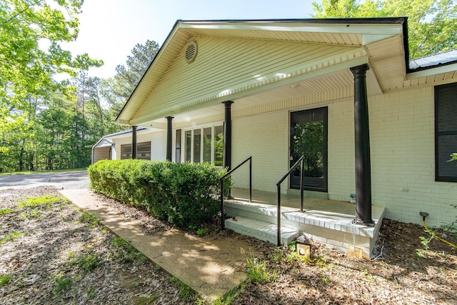 view of side of home with brick siding and covered porch