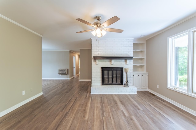 unfurnished living room featuring a wall unit AC, a ceiling fan, wood finished floors, baseboards, and ornamental molding