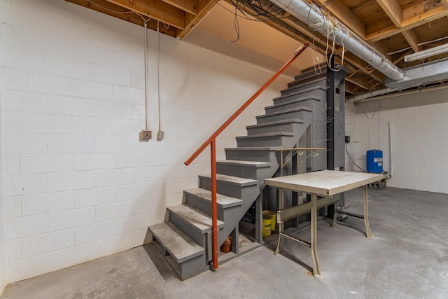 unfinished below grade area featuring concrete block wall and stairs