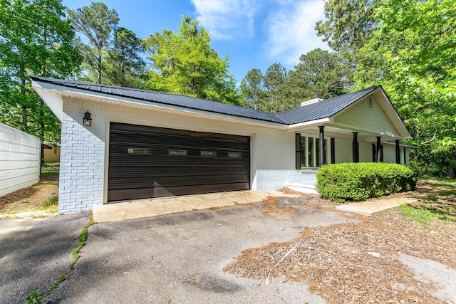 view of front of home featuring brick siding, metal roof, and aphalt driveway