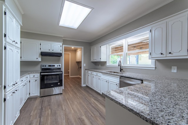 kitchen featuring wood finished floors, white cabinetry, under cabinet range hood, a sink, and appliances with stainless steel finishes