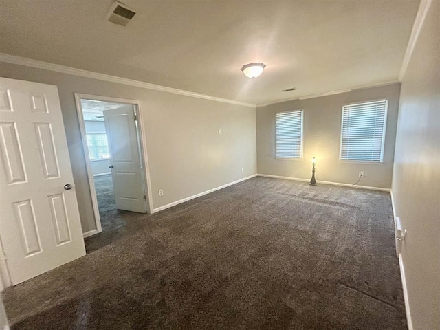 unfurnished room featuring baseboards, ornamental molding, dark carpet, and visible vents