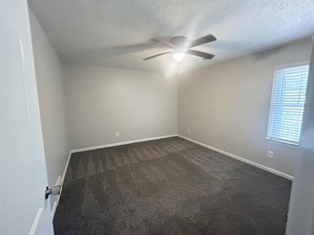 empty room with dark colored carpet, a textured ceiling, ceiling fan, and baseboards