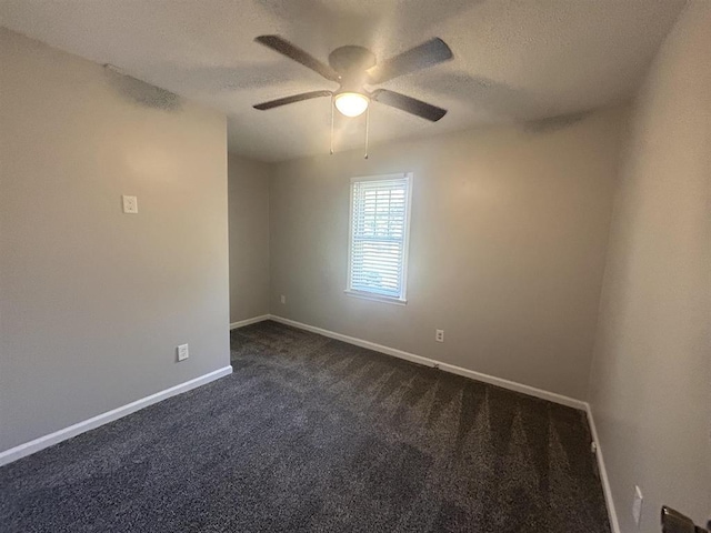 spare room with dark colored carpet, a ceiling fan, baseboards, and a textured ceiling