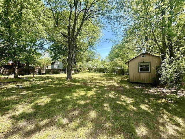 view of yard with a storage shed, fence, and an outdoor structure