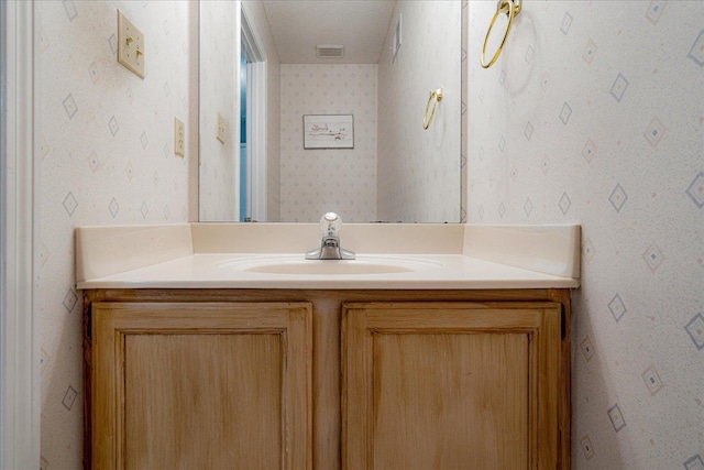 bathroom featuring wallpapered walls, visible vents, and vanity