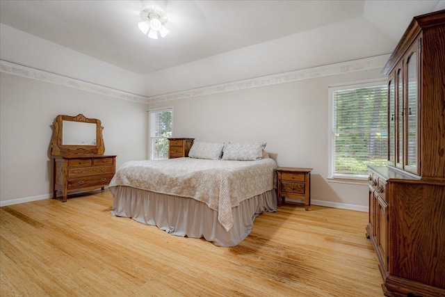 bedroom with baseboards, light wood finished floors, and multiple windows