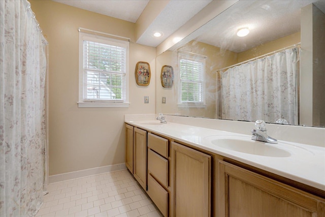 bathroom featuring baseboards, double vanity, tile patterned floors, and a sink