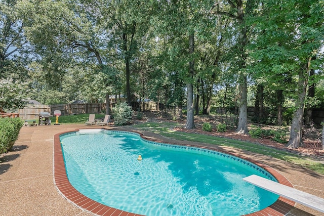 view of swimming pool featuring a diving board, a fenced in pool, a fenced backyard, and a patio area