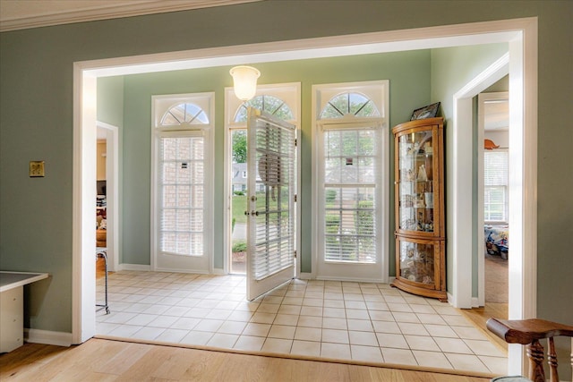 doorway to outside featuring baseboards, ornamental molding, and light tile patterned floors