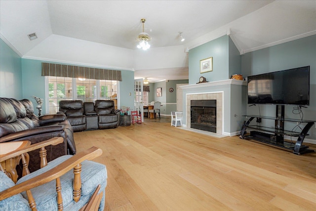 living area featuring a ceiling fan, visible vents, a tile fireplace, wood finished floors, and ornamental molding
