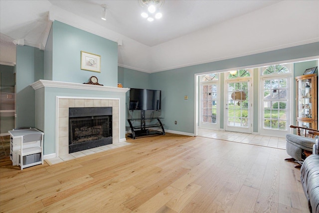 living area with a tiled fireplace, baseboards, crown molding, and hardwood / wood-style flooring