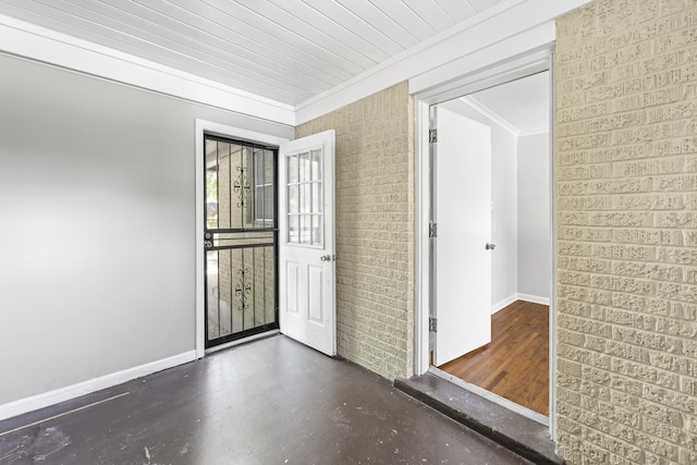 empty room with crown molding, baseboards, and brick wall