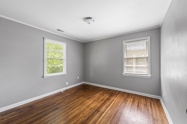 unfurnished room with visible vents, baseboards, crown molding, and wood finished floors