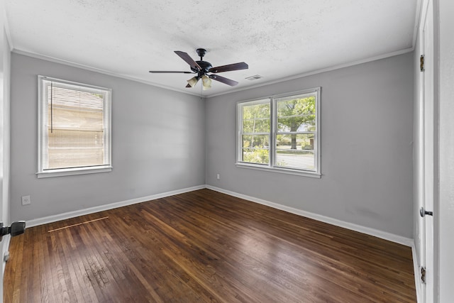 empty room with crown molding, visible vents, baseboards, hardwood / wood-style flooring, and a ceiling fan