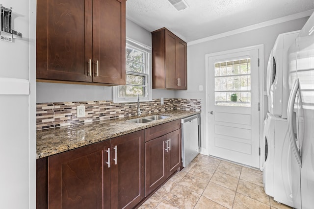 kitchen featuring plenty of natural light, stacked washer / dryer, visible vents, appliances with stainless steel finishes, and a sink