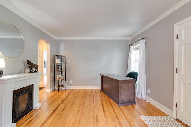 office space featuring crown molding, arched walkways, light wood-style flooring, and a glass covered fireplace