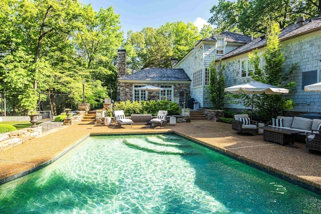 exterior space with a patio, a chimney, an outdoor living space, and an outdoor pool