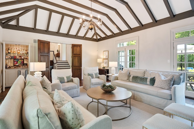 living area featuring beam ceiling, stairway, high vaulted ceiling, a bar, and an inviting chandelier