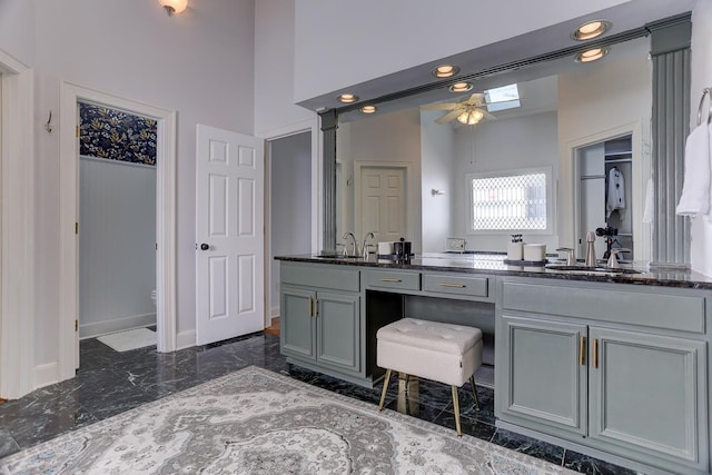 bathroom with a sink, ceiling fan, double vanity, and marble finish floor