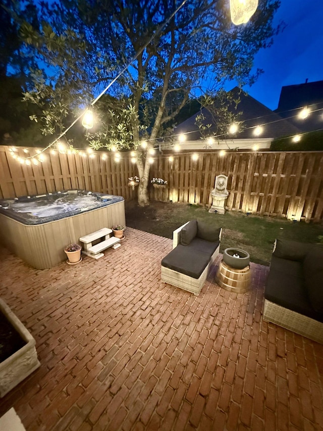 patio at twilight featuring a hot tub and a fenced backyard