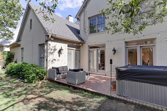 back of property with a patio, brick siding, an outdoor living space, a shingled roof, and a hot tub