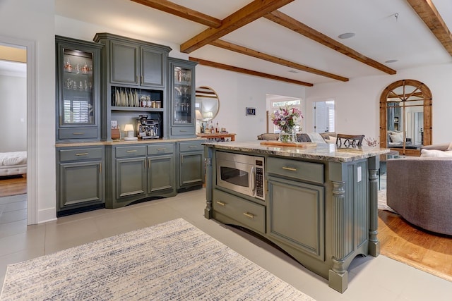bar featuring light tile patterned floors, stainless steel microwave, and beam ceiling