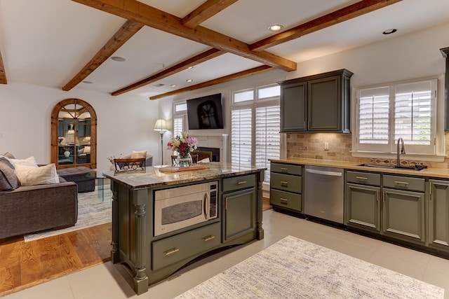 kitchen featuring a sink, beamed ceiling, stainless steel appliances, and open floor plan