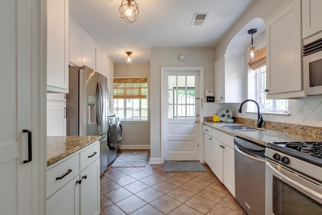 kitchen with white cabinets, appliances with stainless steel finishes, light stone counters, a sink, and visible vents
