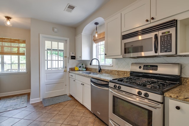 kitchen with backsplash, visible vents, a sink, white cabinets, and stainless steel appliances