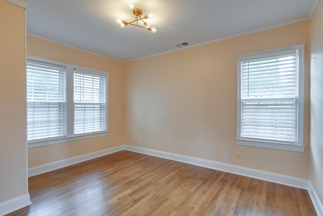 spare room with baseboards, ornamental molding, light wood-type flooring, and visible vents