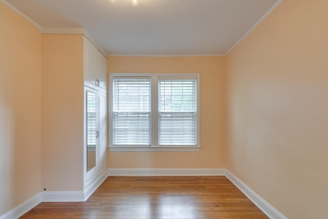 empty room with baseboards, ornamental molding, and wood finished floors