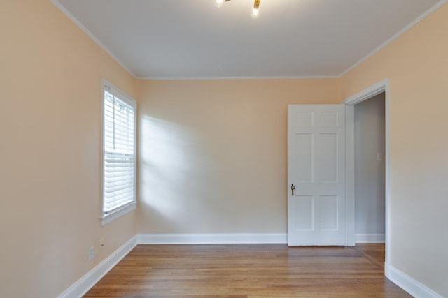 unfurnished room with light wood-type flooring, ornamental molding, and baseboards
