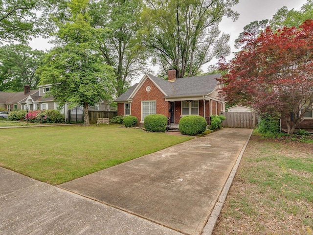 view of front of house featuring fence, a front lawn, brick siding, a chimney, and driveway