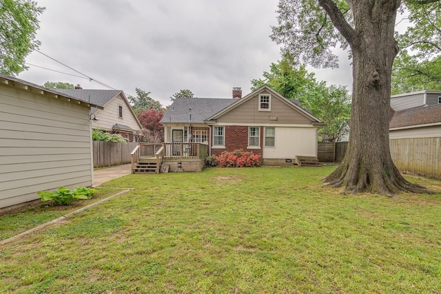 rear view of house featuring brick siding, a deck, a fenced backyard, and a lawn
