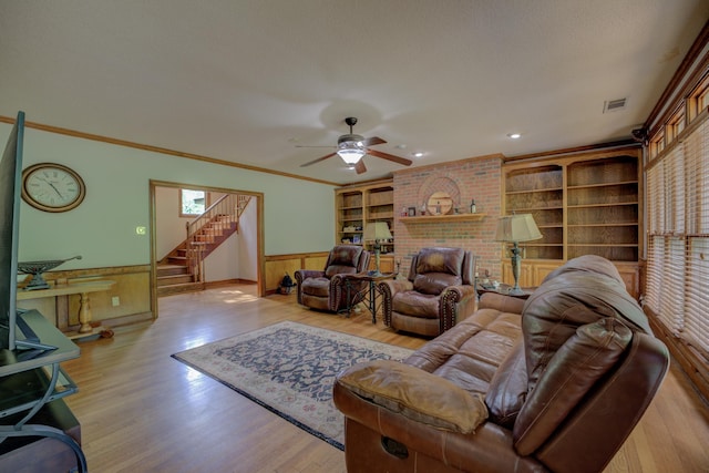 living room with ceiling fan, a wainscoted wall, wood finished floors, visible vents, and stairway