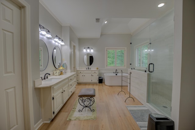 full bathroom featuring crown molding, a stall shower, wood finished floors, a sink, and a soaking tub
