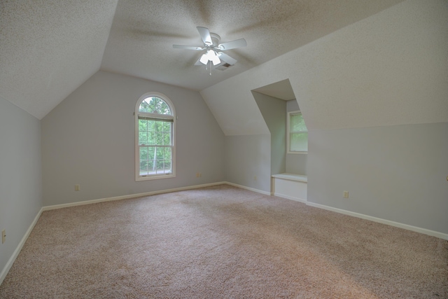 bonus room with a textured ceiling, ceiling fan, vaulted ceiling, and light carpet