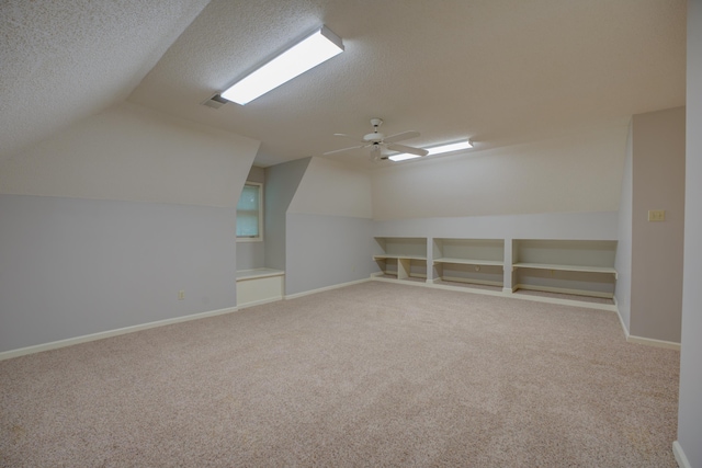 additional living space with carpet floors, visible vents, lofted ceiling, a textured ceiling, and a ceiling fan