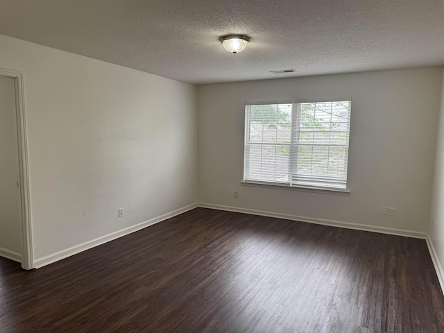 unfurnished room with baseboards, dark wood-style flooring, a textured ceiling, and visible vents