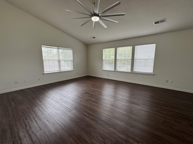 spare room featuring a ceiling fan, dark wood-type flooring, lofted ceiling, and visible vents