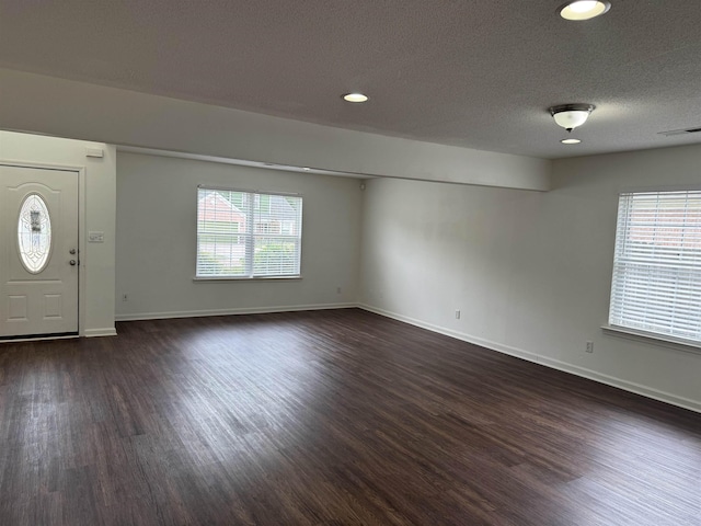 foyer with a textured ceiling, visible vents, and dark wood-style floors