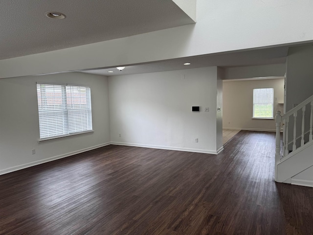 unfurnished room featuring stairs, baseboards, and dark wood-type flooring