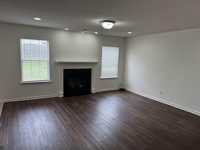 unfurnished living room with visible vents, a fireplace with flush hearth, dark wood-style flooring, and baseboards