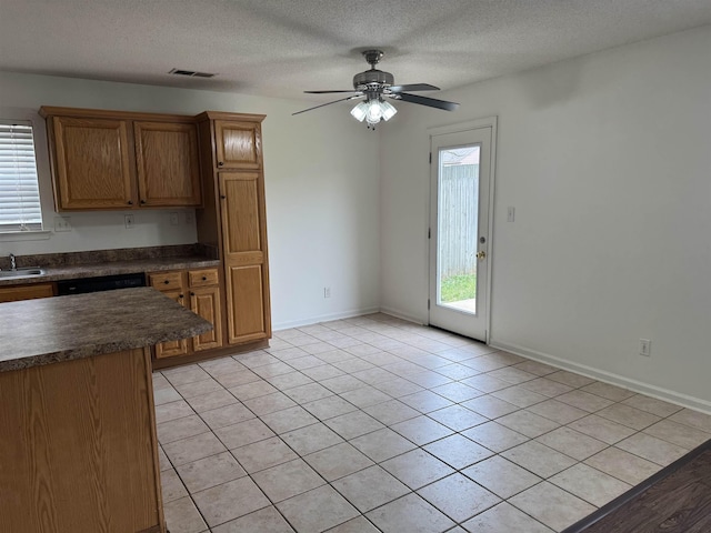 kitchen featuring dark countertops, a sink, a ceiling fan, light tile patterned floors, and visible vents