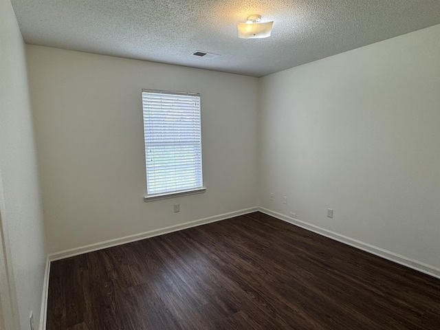 unfurnished room featuring baseboards, a textured ceiling, visible vents, and dark wood finished floors