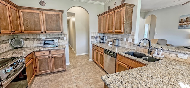 kitchen with crown molding, arched walkways, appliances with stainless steel finishes, and a sink