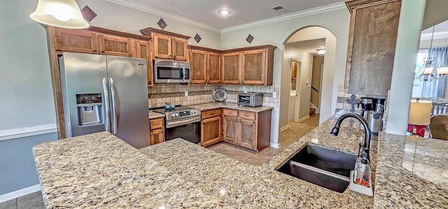 kitchen featuring brown cabinets, appliances with stainless steel finishes, a sink, tasteful backsplash, and visible vents